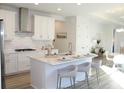 Modern white kitchen with stainless steel appliances, a central island with seating, and an open layout at 229 Vistera Blvd, North Venice, FL 34275