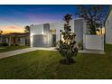 Modern home with a gray brick facade, tidy lawn and walkway and magnolia tree at dusk at 3508 E 11Th Ave, Tampa, FL 33605