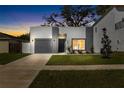 Modern home featuring a gray brick facade, gray garage door, tidy lawn and walkway at dusk at 3508 E 11Th Ave, Tampa, FL 33605