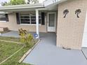 View of the home's entrance, featuring a covered porch, a decorative palm tree emblem, and brick accents at 7352 Sequoia Dr, New Port Richey, FL 34653