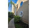 A charming condo exterior showcases unique round windows, complemented by lush landscaping and a sidewalk at 8744 54Th W Ave # 8744, Bradenton, FL 34210