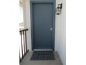 Close-up of a stylish steel front door with dark trim and a 'Welcome' mat, illuminated by a wall-mounted lantern at 3102 W Horatio St # 21, Tampa, FL 33609
