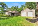 Exterior of home and detached two-car garage with generous lawn and mature trees at 3703 Cooper Rd, Plant City, FL 33565