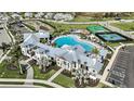 Aerial view of the luxury community pool area, showcasing spacious pool deck, elegant clubhouse, and lush palm trees at 4720 Cassonade Cv, Bradenton, FL 34211