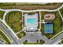 Aerial view featuring pool, playground, tennis courts and a parking area at 7448 Cabin Ln, Sarasota, FL 34240