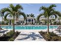 Resort-style community pool with lounge chairs, umbrellas and lush tropical landscaping at 18068 Cherished Loop, Bradenton, FL 34211