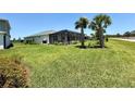 Expansive backyard featuring a screened-in pool area, lush green lawn, and palm trees at 43819 Cattleman Dr, Punta Gorda, FL 33982