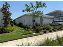 Well-manicured lawn and landscaping surrounding a lovely single-story home with neutral colors at 43819 Cattleman Dr, Punta Gorda, FL 33982