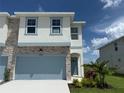 Charming two-story home featuring stone accents, a blue garage door, and inviting landscaping at 14004 Emerald Fields Dr, Hudson, FL 34667
