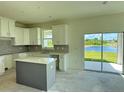 Bright kitchen featuring white cabinetry, an island, granite countertops, and sliding glass doors at 14004 Emerald Fields Dr, Hudson, FL 34667