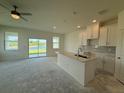 Bright kitchen featuring an island, stainless sink, white cabinetry and an outdoor view at 14012 Emerald Fields Dr, Hudson, FL 34667