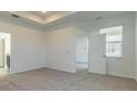 Comfortable bedroom with neutral carpet, tray ceiling, and doorway leading to other rooms at 16866 Fiesta Dr, Port Charlotte, FL 33953