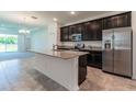 Modern kitchen featuring dark wood cabinets, stainless steel appliances, and granite countertops with an island at 16866 Fiesta Dr, Port Charlotte, FL 33953