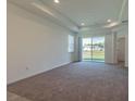 Bright living room with neutral carpet, recessed lighting, and sliding glass door to the backyard at 16866 Fiesta Dr, Port Charlotte, FL 33953