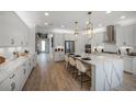 Bright white kitchen features an island with seating, stainless steel appliances, and modern pendant lighting at 1688 Lugano Cir, Nokomis, FL 34275