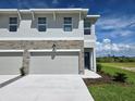 Charming townhome featuring a stone facade, two-car garage, and a well-manicured lawn at 13904 Emerald Fields Dr, Hudson, FL 34667