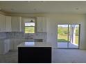 Modern kitchen with white cabinets, quartz countertops, and a black kitchen island at 13904 Emerald Fields Dr, Hudson, FL 34667