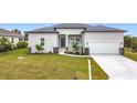 Charming single-story home featuring a neutral color scheme, two-car garage, and a well-manicured lawn at 13527 Ainsworth Ln, Port Charlotte, FL 33981