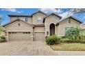 Two-story house with tan exterior, three-car garage, and landscaping at 1005 Sonesta Ave, Brandon, FL 33511