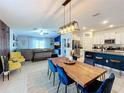 Open-concept dining area with wood table, blue velvet chairs, modern light fixture, and views of the living room and kitchen at 12764 Weston Oaks Ln, Riverview, FL 33579