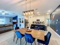Open-concept dining area featuring a wood table with blue velvet chairs and modern light fixture, adjacent to the kitchen at 12764 Weston Oaks Ln, Riverview, FL 33579