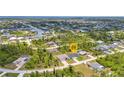 Aerial view of a home nestled among lush greenery and neighboring houses near the water at 8489 Topeka Cir, Port Charlotte, FL 33981