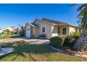 Tan single-story house with a landscaped lawn, a brick garage, and a bench at 5846 Greenbriar Ct, Zephyrhills, FL 33542