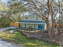 Charming home surrounded by mature trees, featuring bright blue doors and a welcoming front porch at 10020 Jungle St, New Port Richey, FL 34654