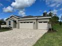 Well-maintained single-story house boasts a three-car garage, attractive stone driveway, and landscaped front yard at 9049 Players Dr, Weeki Wachee, FL 34613