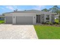 Well maintained lawn and landscaping highlight this single-story home with a two car garage and brick paver driveway at 9071 Players Dr, Weeki Wachee, FL 34613