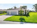 Well-maintained front yard featuring lush grass and a charming, modern single-story home at 9071 Players Dr, Weeki Wachee, FL 34613