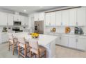 Modern kitchen features white cabinets, stainless steel appliances, and a large island with bar stool seating at 9093 Players Dr, Weeki Wachee, FL 34613