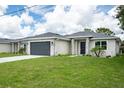 Attractive single-story home featuring a gray garage door, stone accents, and a lush green lawn at 183 Wright Drive, Rotonda West, FL 33947