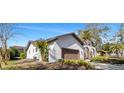 Stunning home exterior featuring a two-car garage, beautiful landscaping, and classic stucco walls at 4907 Parson Brown Ln, Palm Harbor, FL 34684