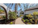 Inviting front entrance featuring a walkway through landscaped beds and white archway at 4907 Parson Brown Ln, Palm Harbor, FL 34684