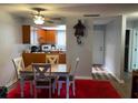 Cozy dining room with a red rug and a dining table that leads to a kitchen and a ceiling fan at 215 Valencia Blvd # 212, Belleair Bluffs, FL 33770