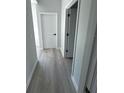 Hallway with grey wood floors and white doors with black hardware at 104 Australian Dr, Rotonda West, FL 33947