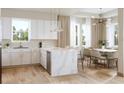 Open concept kitchen with white cabinets, marble island, stainless appliances, and dining area at 125 Baytree Dr, Rotonda West, FL 33947