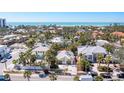 An aerial view of houses surrounded by lush greenery with the ocean horizon in the background at 115 N Blvd Of The Presidents, Sarasota, FL 34236