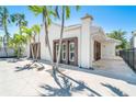 Beautiful home with a light-colored facade and a tiled walkway, framed by lush palms and a serene blue sky at 115 N Blvd Of The Presidents, Sarasota, FL 34236