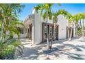 Angle shot of building showing a light-colored exterior with dark window frames and palms, complemented by a stone-tiled walkway at 115 N Blvd Of The Presidents, Sarasota, FL 34236