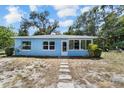 Charming, light blue one-story home with lush greenery and a welcoming front entrance at 1724 Harbor Dr, Clearwater, FL 33755