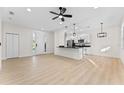 Bright, modern living room featuring an open layout with a ceiling fan, white walls, and wood flooring at 2503 Dumont Ln, North Port, FL 34286