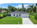 Picture-perfect single-Gathering home featuring lush green lawn, and modern gray driveway and exterior accents at 17041 Malta Ave, Port Charlotte, FL 33954