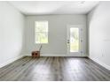 Open concept living room with a large window, glass door, and gray wood-look flooring at 23113 Brewer Ave, Punta Gorda, FL 33980