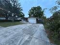 View of a single-story home with a one-car garage, car port and long driveway bordered by rose bushes at 1912 W Clinton St, Tampa, FL 33604