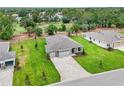 Aerial view of a home with a three-car garage, stone accents, and lush, well-maintained landscaping at 9143 Players Dr, Weeki Wachee, FL 34613