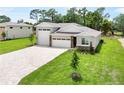 A modern designed home with a three car garage, stone accents, and green lawn at 9177 Players Dr, Weeki Wachee, FL 34613