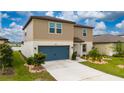 Two-story home with manicured lawn, blue garage door, and a driveway leading to the entrance at 3884 Capri Coast Dr, Plant City, FL 33565