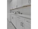 Bright laundry room with white cabinets, modern hardware, sink and stainless steel faucet at 488 Sunset N Rd, Rotonda West, FL 33947